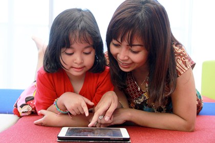  Seorang ibu sedang mendampingi anaknya menggunakan perangkat mobile. Bekerjasama dengan Family Zone, Telkomsel hadirkan layanan Family Protect, sebuah aplikasi mobile yang memungkinkan orang tua  memonitor aktivitas di perangkat seluler anak.